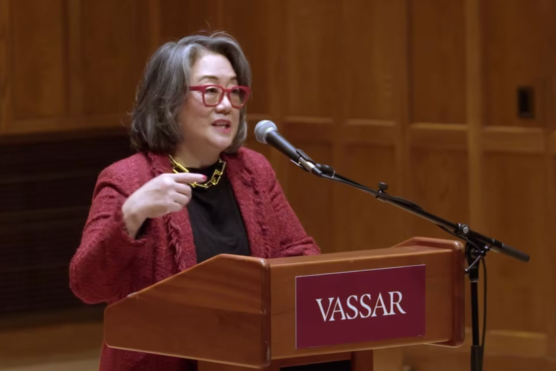 Person standing at a podium speaking into a microphone. The podium has a banner that reads, Vassar.