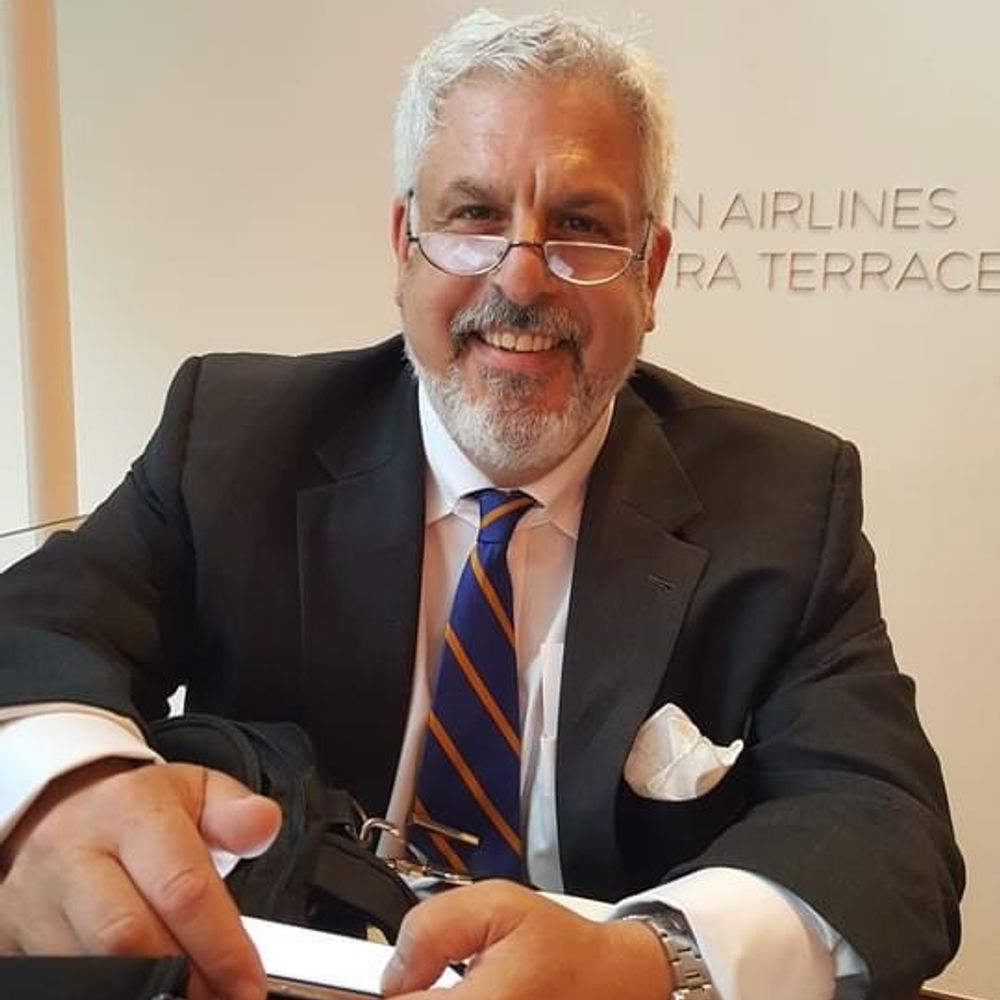 A photo of Steven Cash ’84, a person with gray hair and facial hair, glasses, and a dark suit.