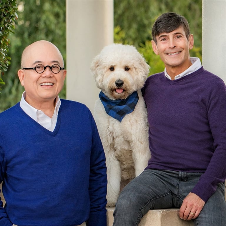 Two people wearing sweaters, one Fritz Friedman '74, pose with a dog between them.