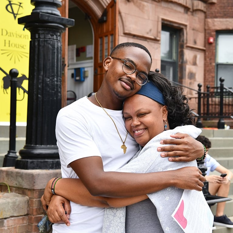 A student and parent hug in front of Davison House on drop-off day at Vassar.