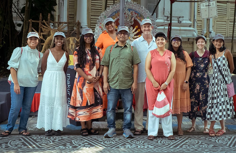A group of people stands in front of a statue depicting the Hindu goddess Devi Durga.