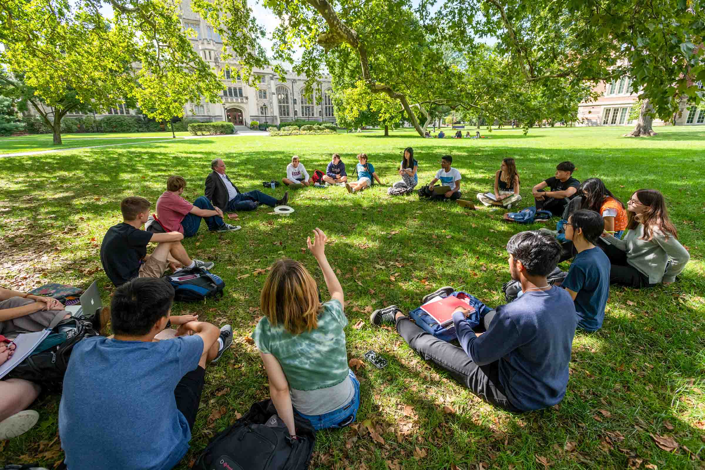 People sitting in wooden, student desks in two lines facing each other.