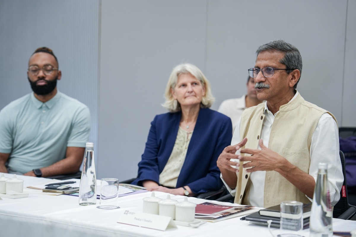Three people sit in a conference room. One is talking, while the others listen.