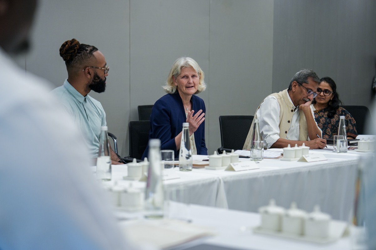 A group of people sit around a table in a conference room.