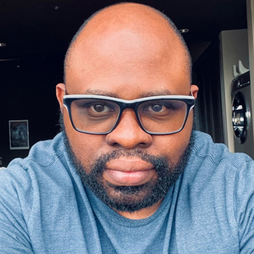 Headshot of a person wearing glasses and a casual shirt, photographed indoors.