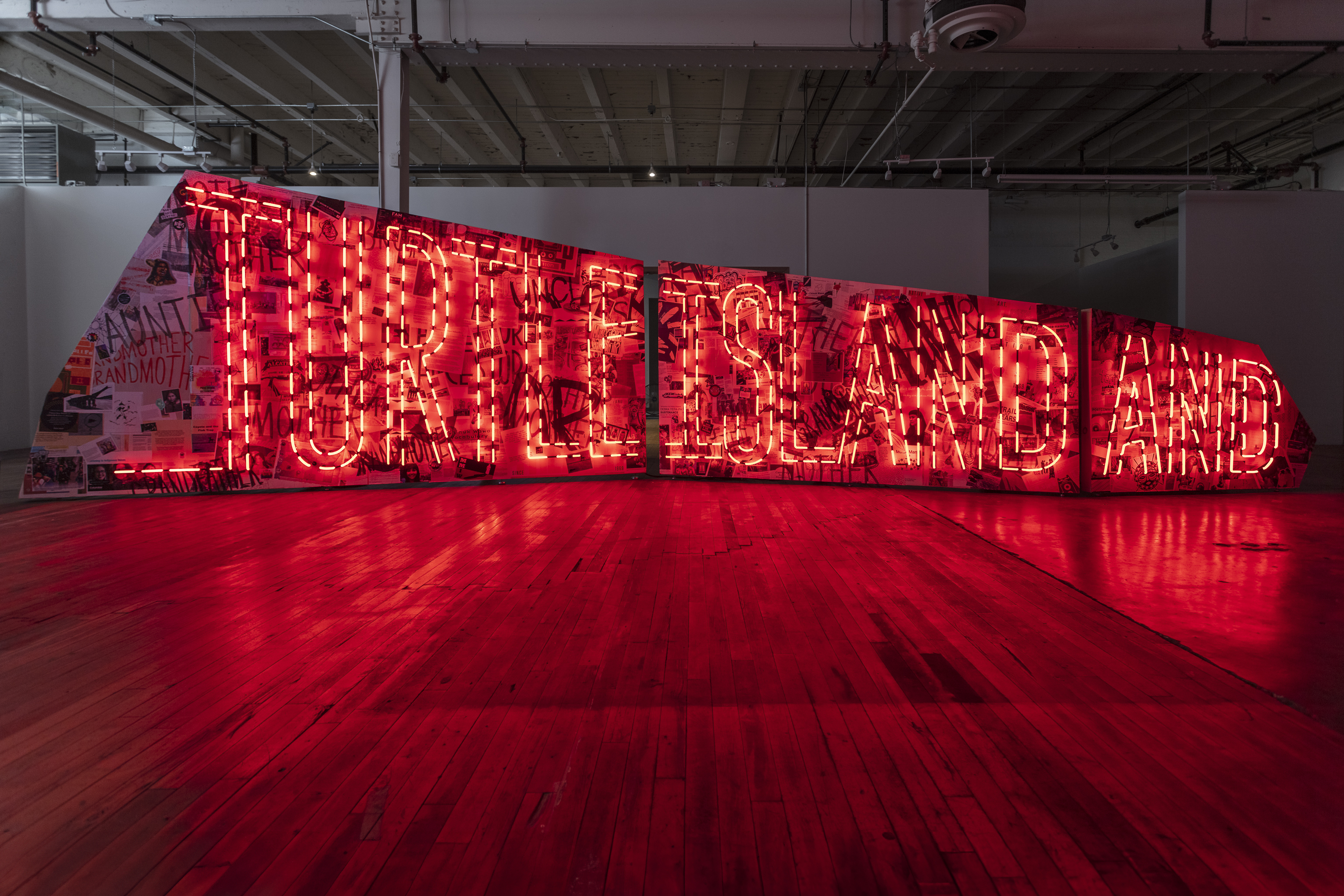 Art installation with red neon sign reading "Turtle Island And"