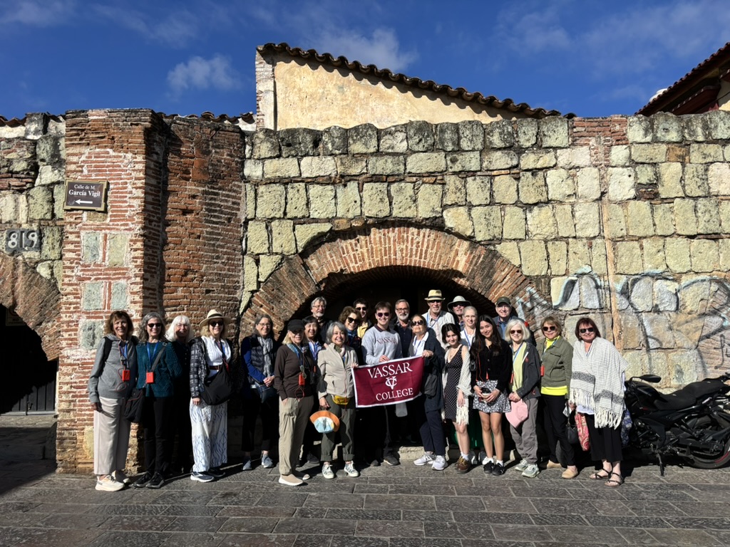 A group shot of Vassar travelers in front of a stone building.