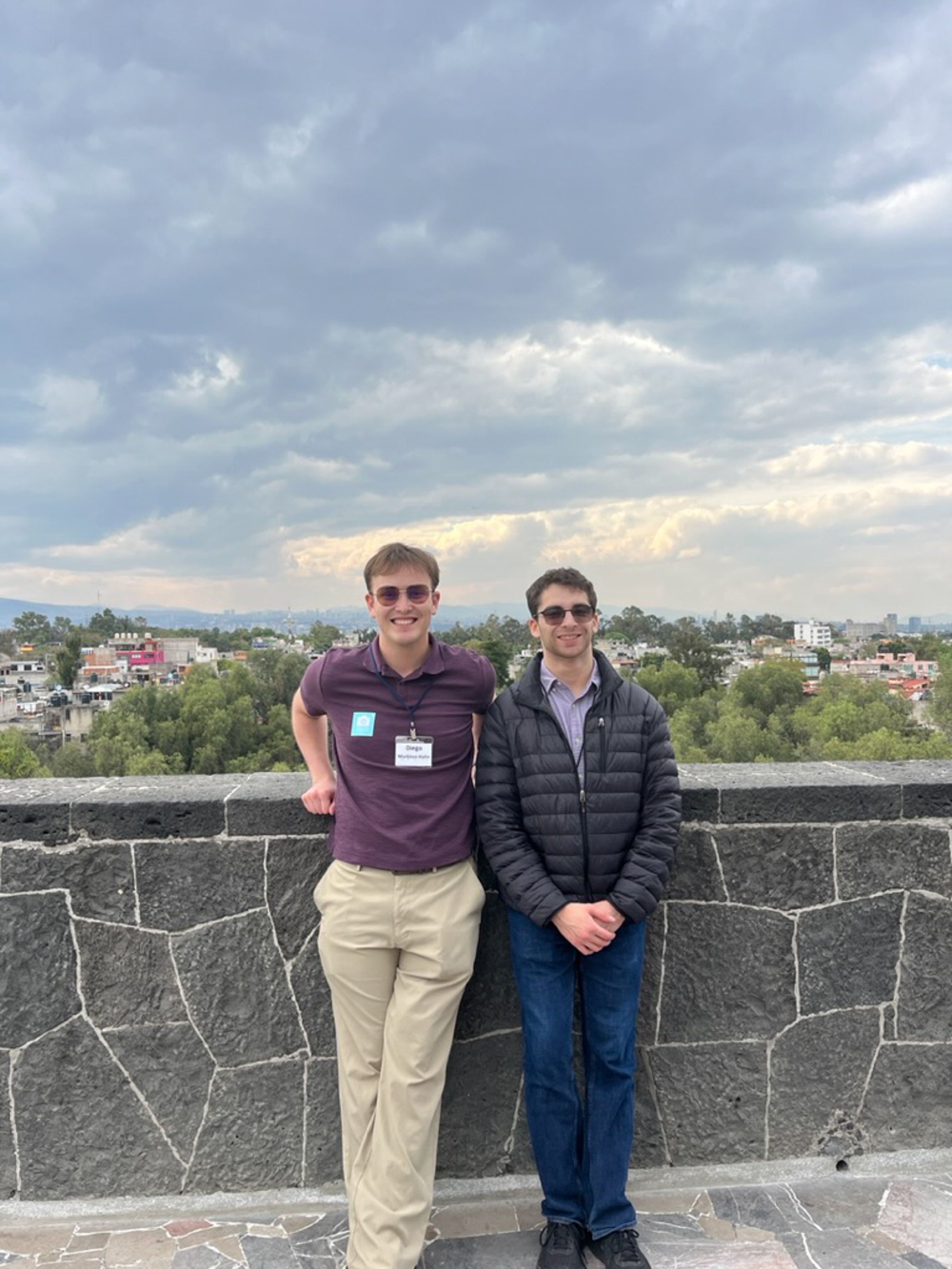 Two men stand on a balcony overlooking Mexican hills