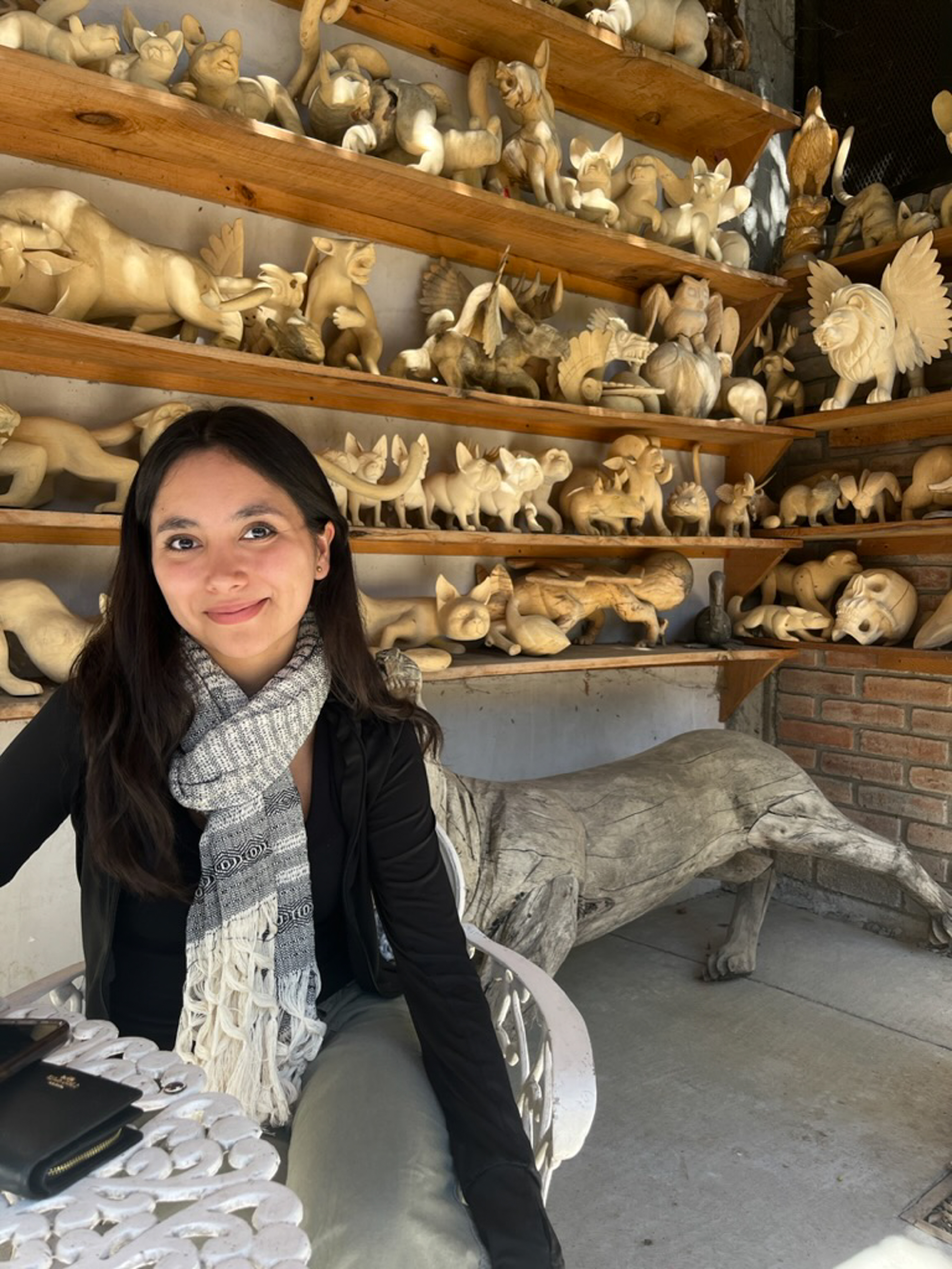 Young woman stands in a pottery studio with clay objects around her.