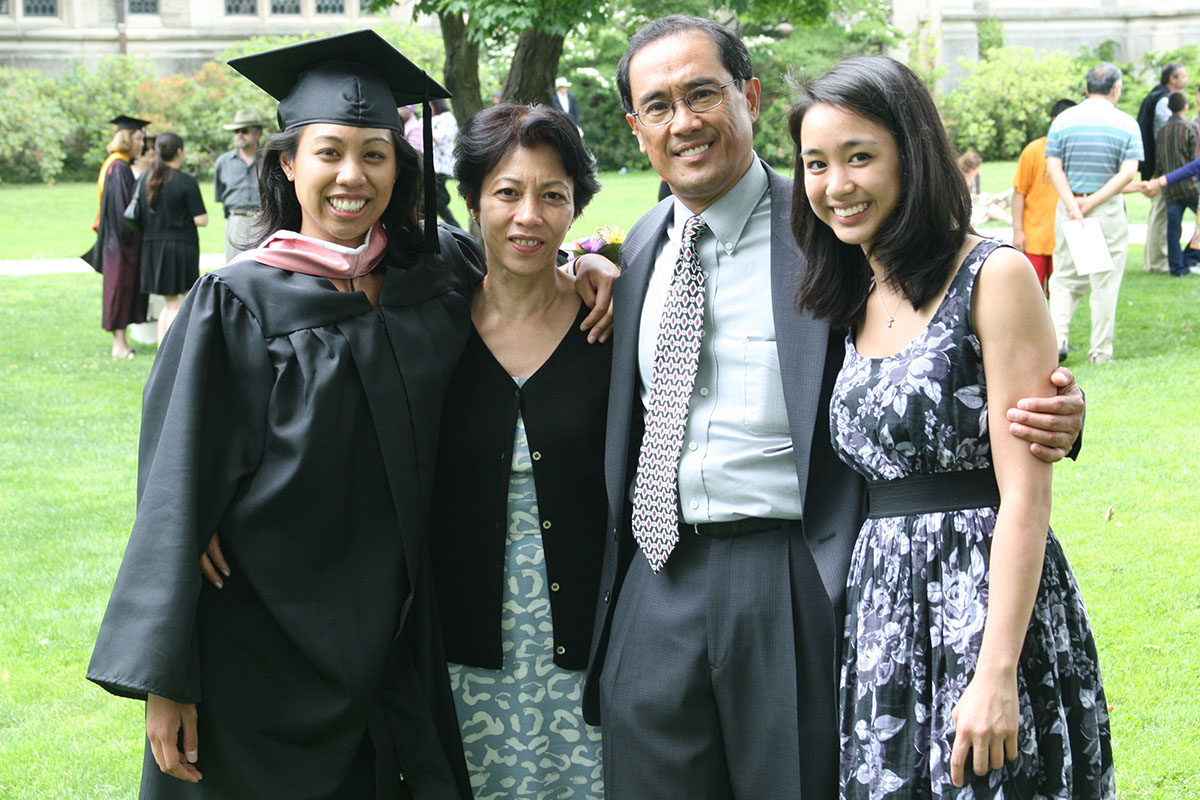 A person in a Vassar graduation cap and robe poses with their family at graduation.