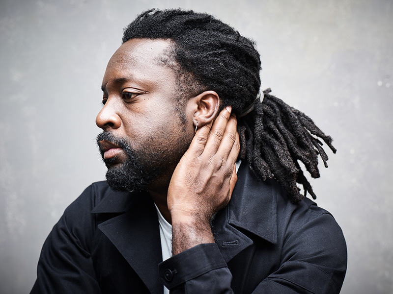 Portrait of subject in profile, looking to the distance with left hand resting on neck and head.