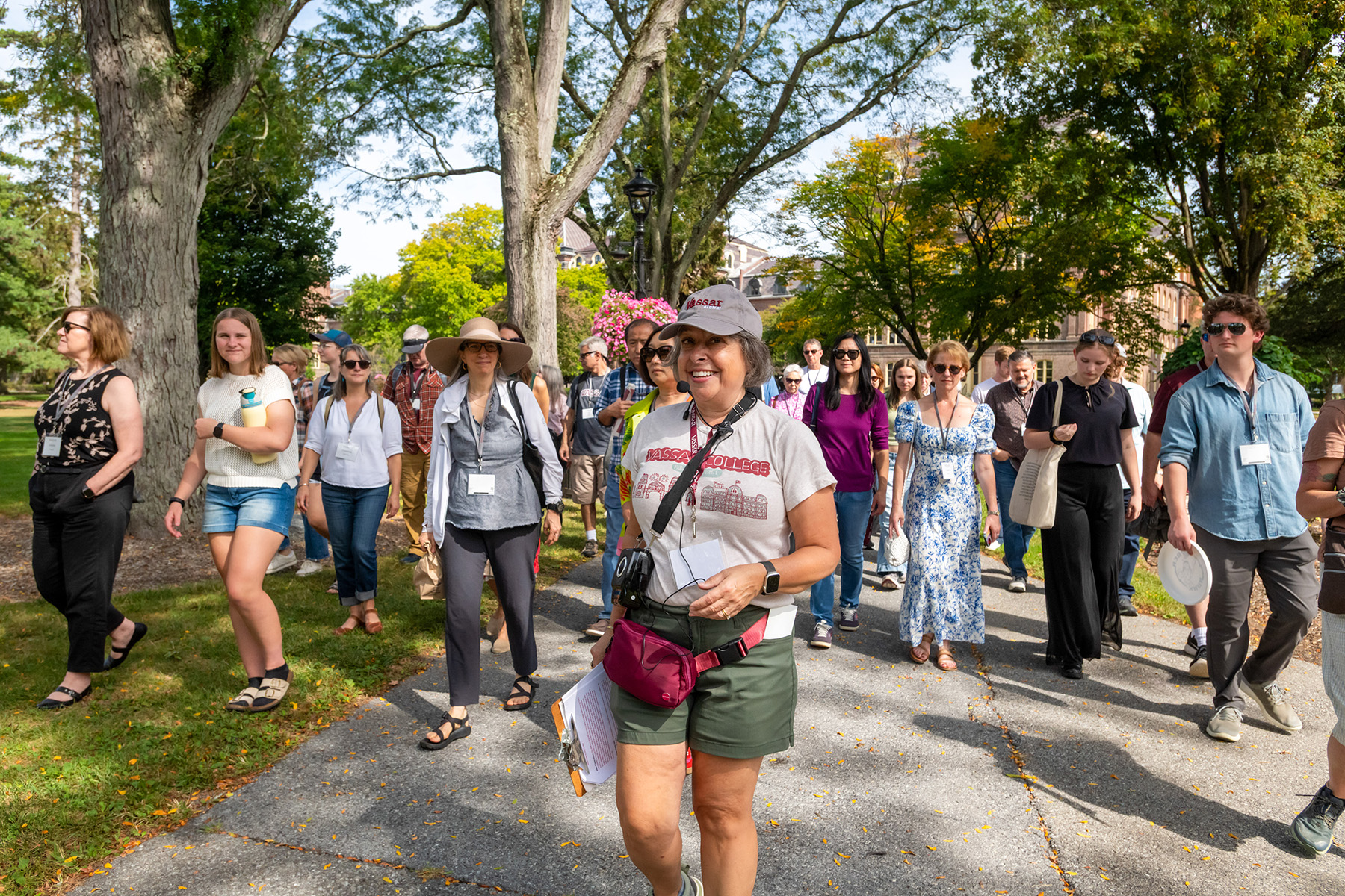 Campus tour group walking along a tree-lined path, led by a guide at the front.