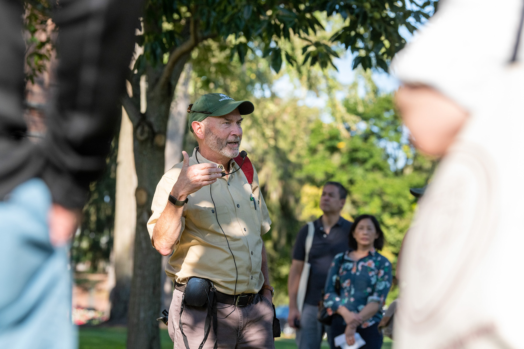 Guide speaking to a group outdoors during a campus tour, wearing a headset microphone.