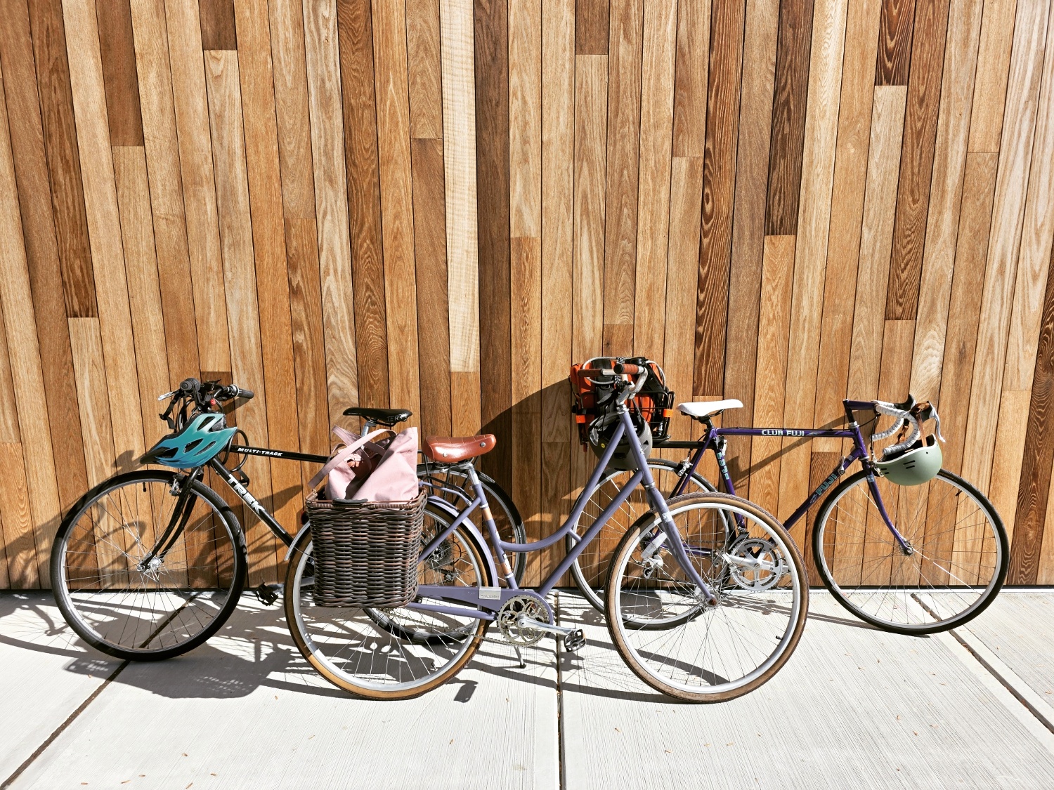 A series of bikes lean against a wooden wall