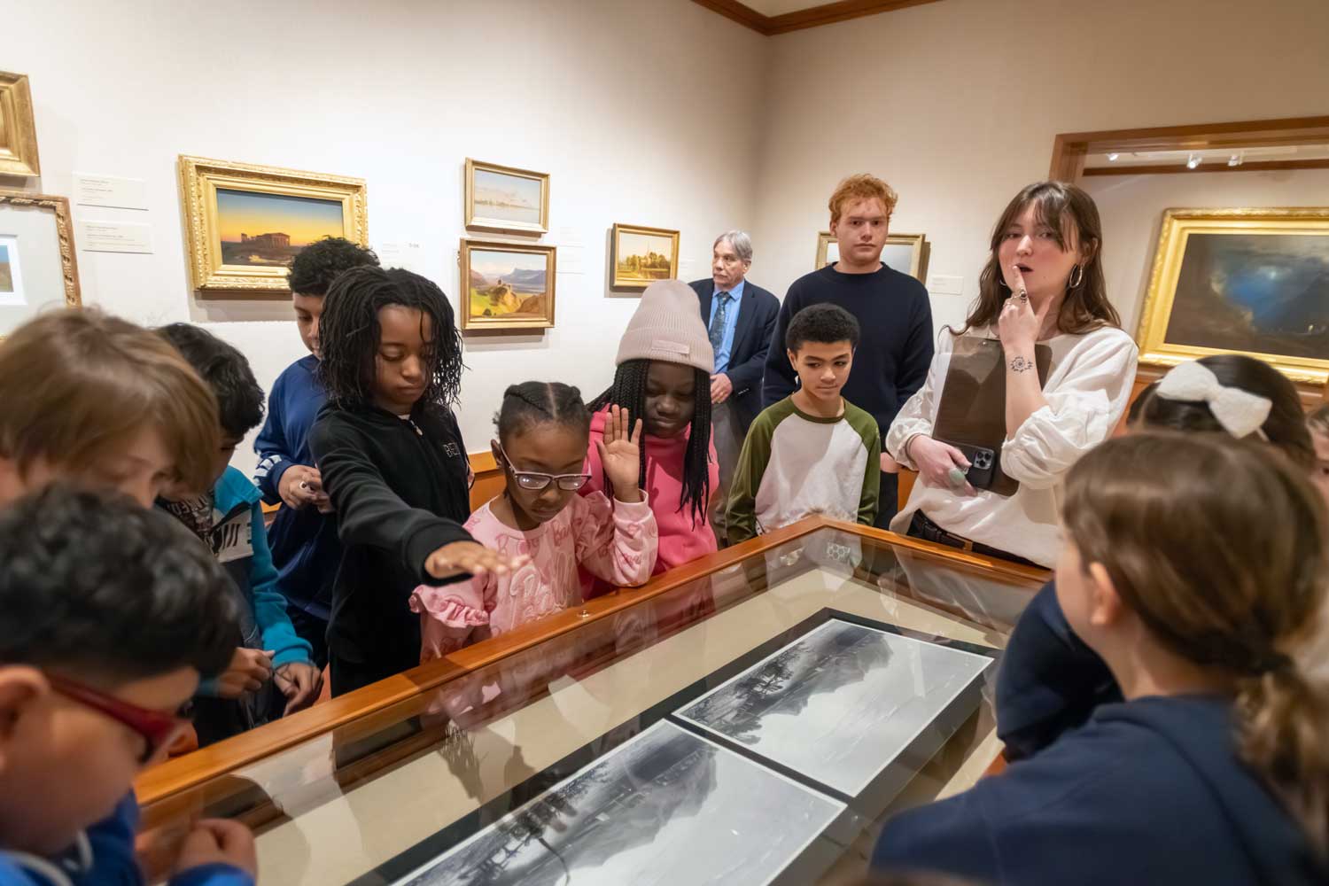 Students gathered around a glass case in a museum looking in.