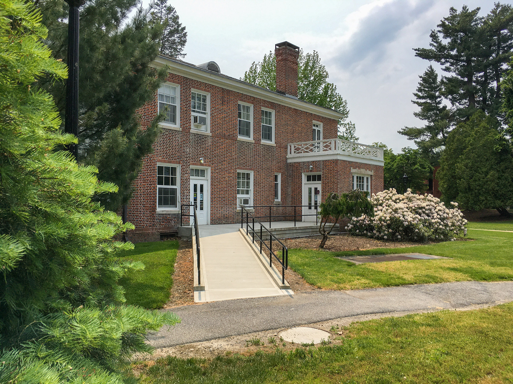 Detail with a concrete ramp with black railings provides access to a ground-floor entrance.