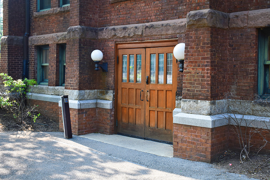Detail of the exterior of the south side of the building as viewed facing west (from the quad), featuring a set of wide double doors with with pull handles.
