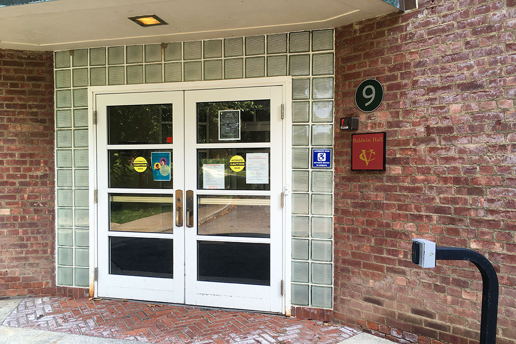 A door with glass blocks and a sign on the side of a brick building.