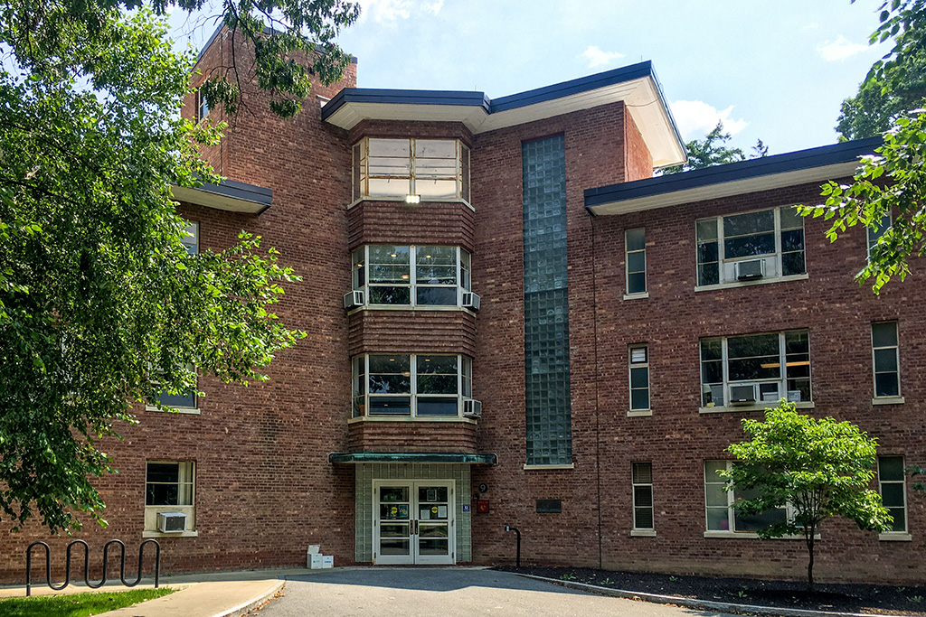 A brick building with trees in the foreground.