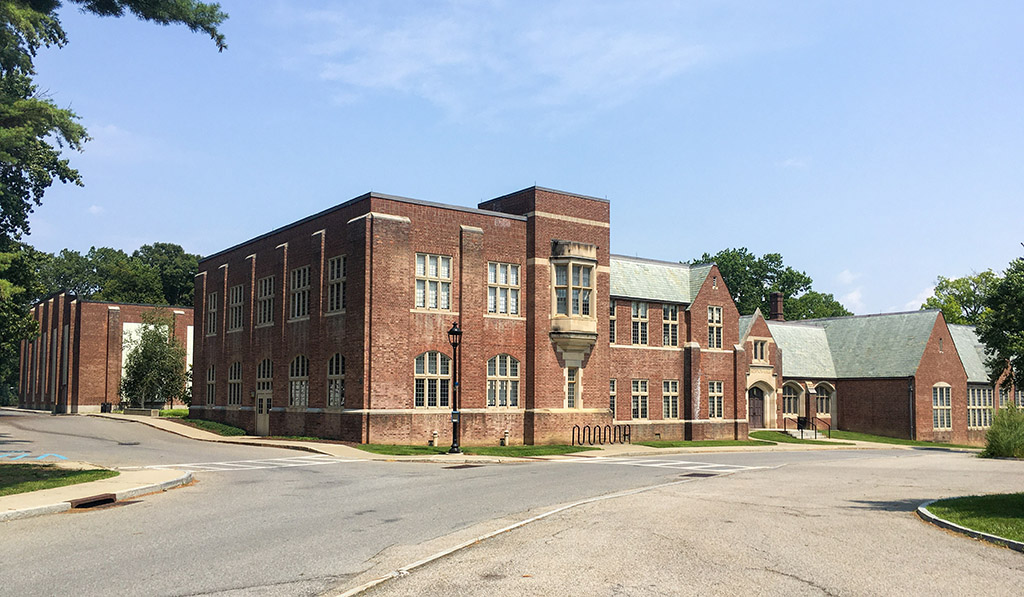 A brick building with a street and trees in the background.