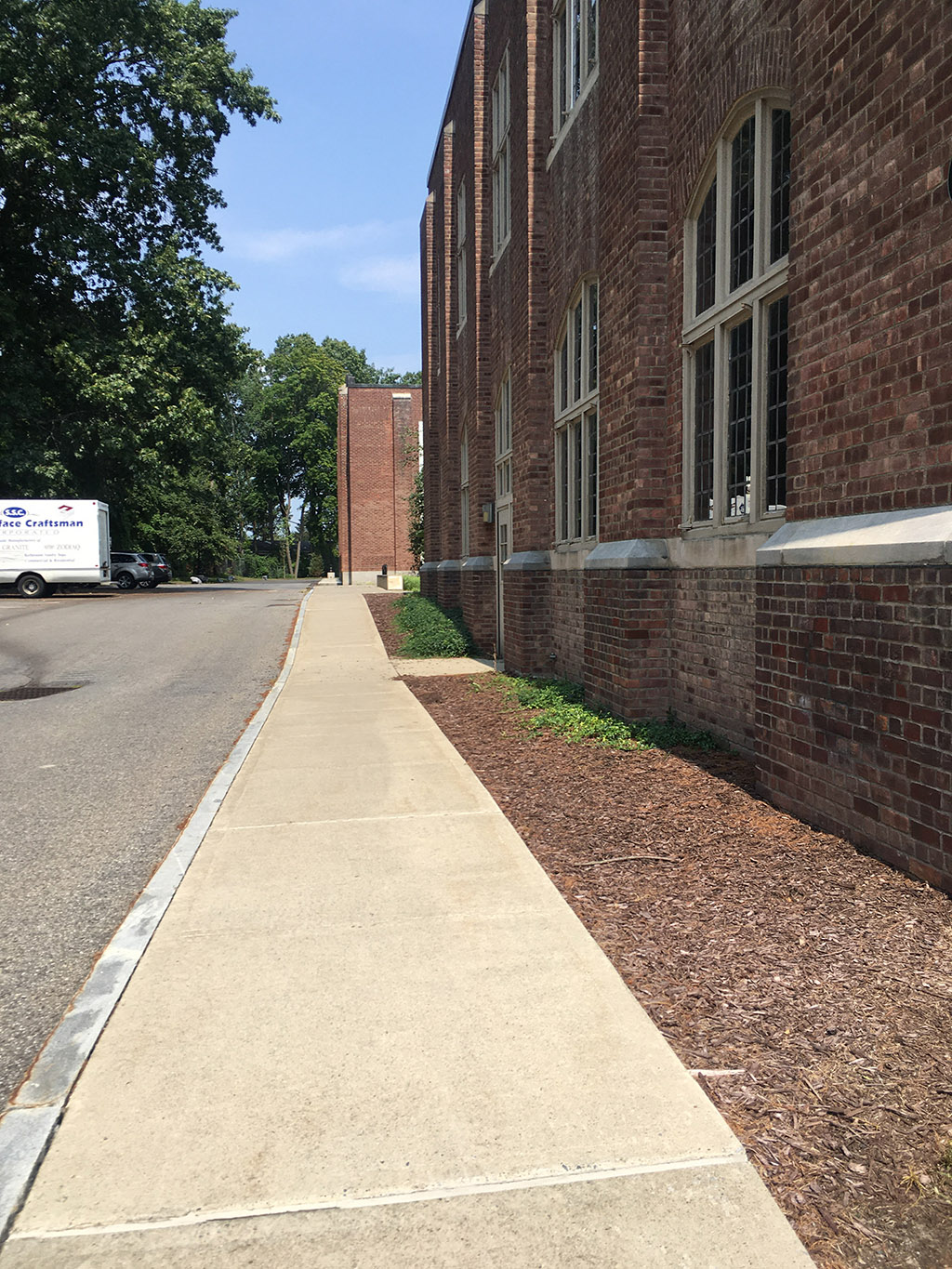 A sidewalk next to a brick building.
