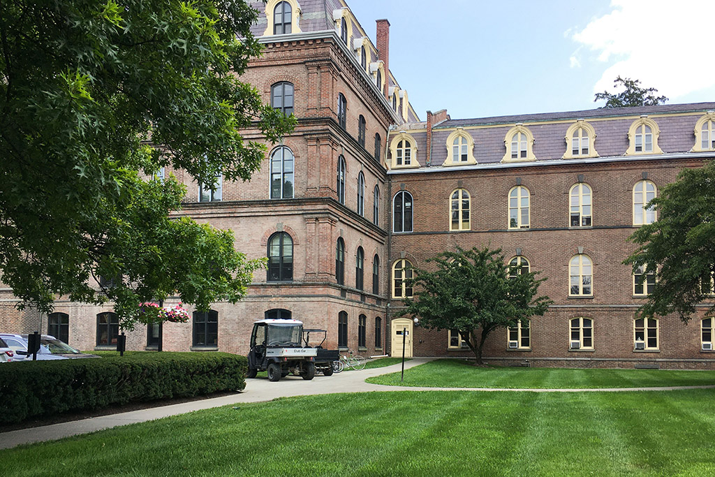 A large brick building with a lawn, and a vehicle parked in the foreground.