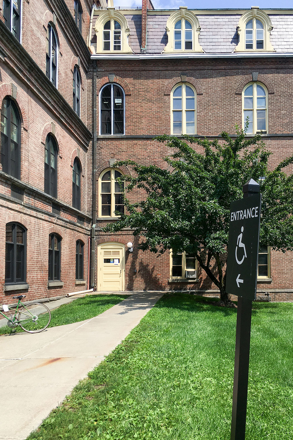 A sign, “Entrance” in front of a brick building.
