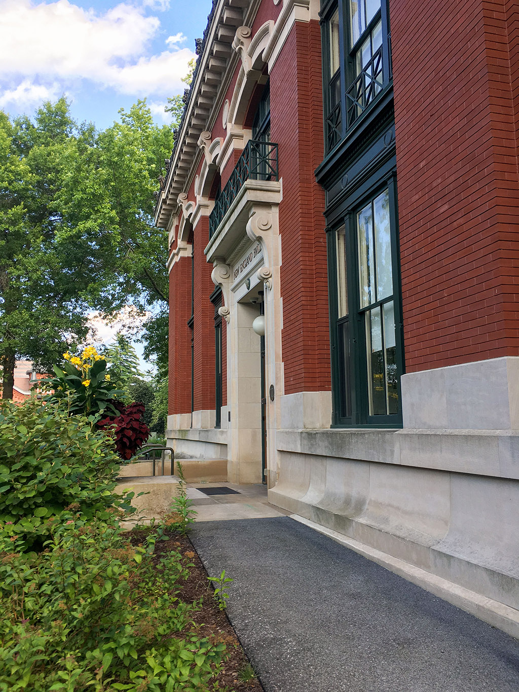 A brick building with trees and a sidewalk.