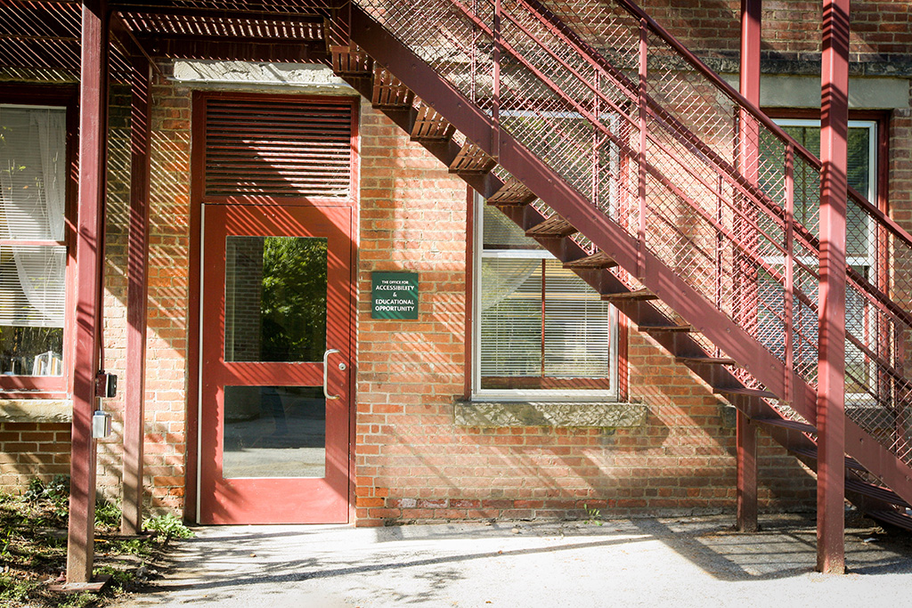 Detail of the entrance at the base of the fire escape, showing a push-to-open button on the fire escape post.