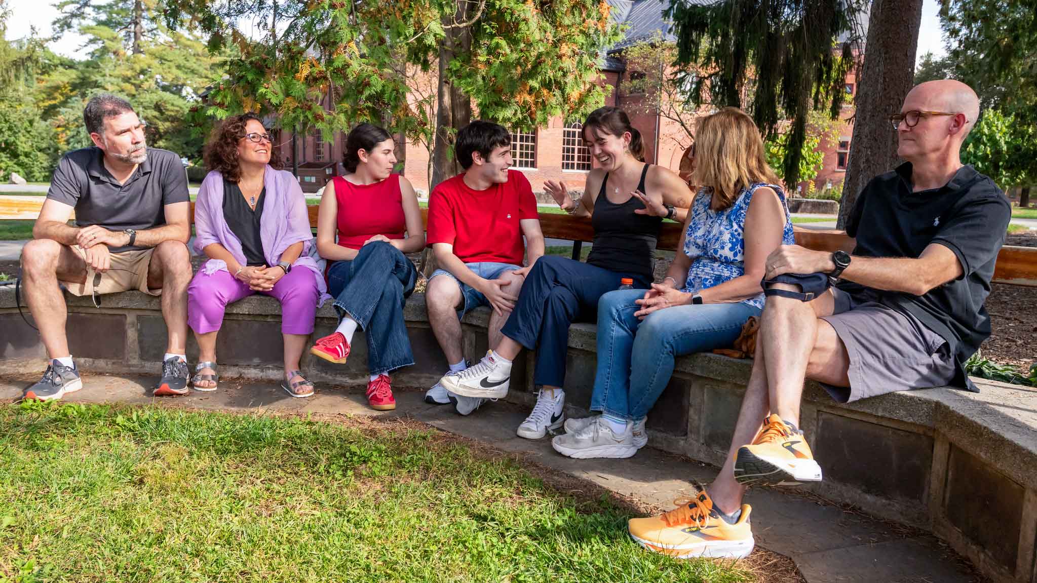 A group of people seated in a semi-circle on an outdoor area.