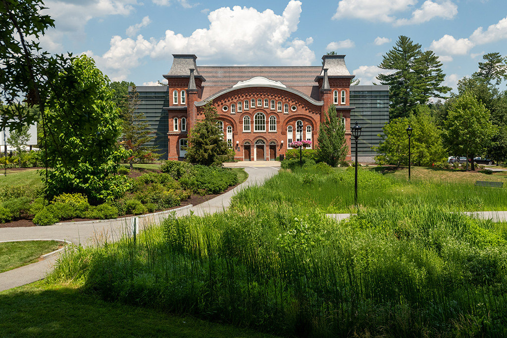 Outside focussed on the front of a brick building with pathways and grasses in front.
