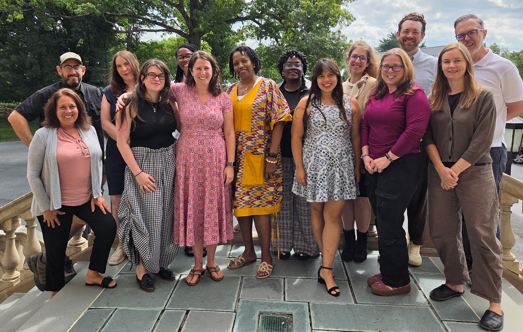 A group of faculty and staff members posing together outdoors on a terrace.