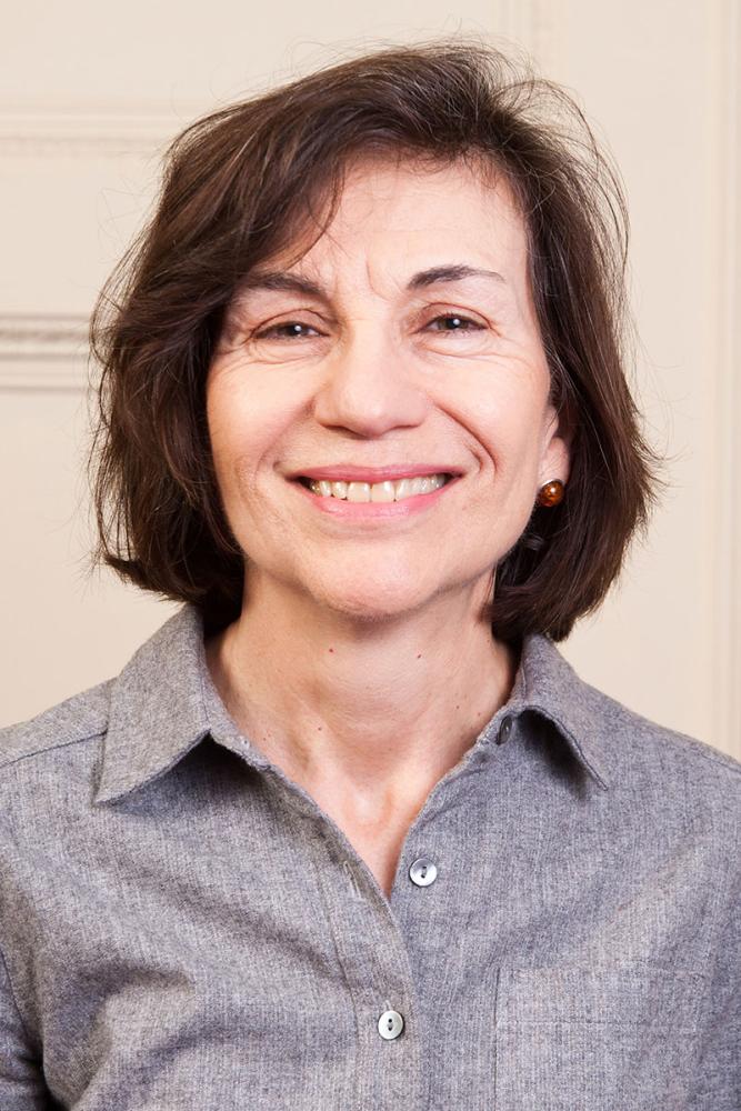 Smiling woman with short brown hair wearing a gray collared shirt.