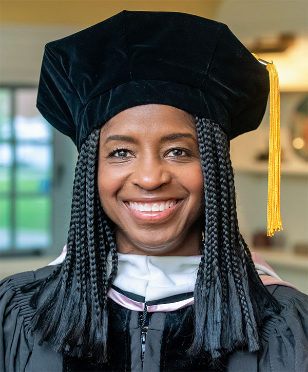 Cynthia Patton ’83, wearing a cap and gown and smiling.