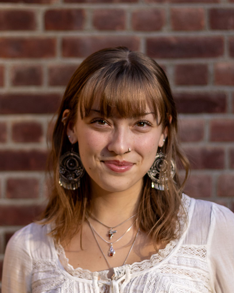 Portrait of a student in front of a brown brick wall.