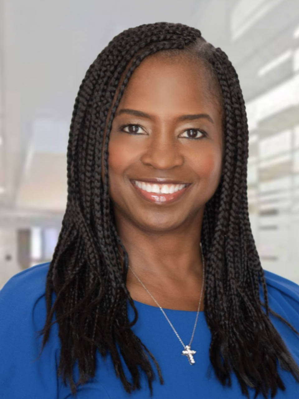 A person with long, black hair in many braids and a blue shirt smiles at the viewer.