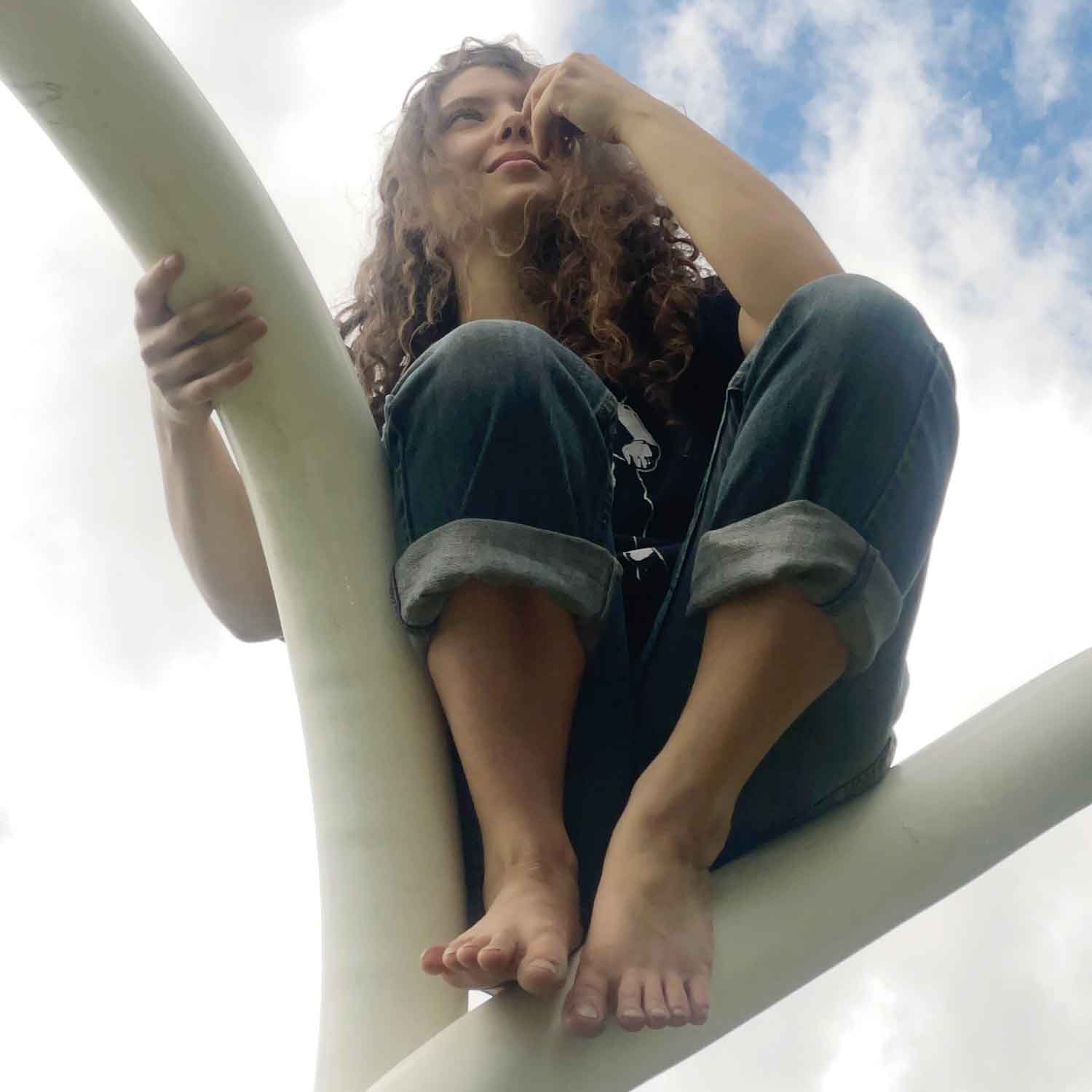 Ella Catalano Mallardi perched in a playground climbing structure.