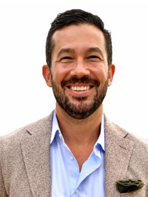 James Beaty ’05, a person with short brown hair and a tan coat, smiles at the camera.