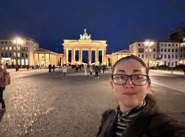 Selfie of a person at night in front of the Brandenburg gate.