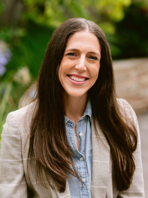 A photo of Alexandria Dempsey ’09, a person with long brown hair and a tan jacket.