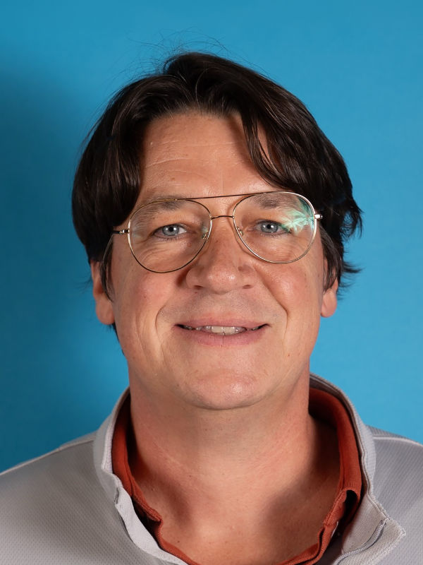 A photo of Dashiell “Dash” Flynn ’99, a person with brown hair, glasses, and a light-colored shirt.