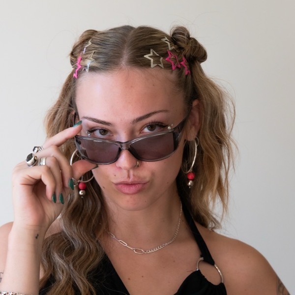 A portrait of Ada Lovelace, a person with brown hair, wearing sunglasses, a black halter top, and jewelry.
