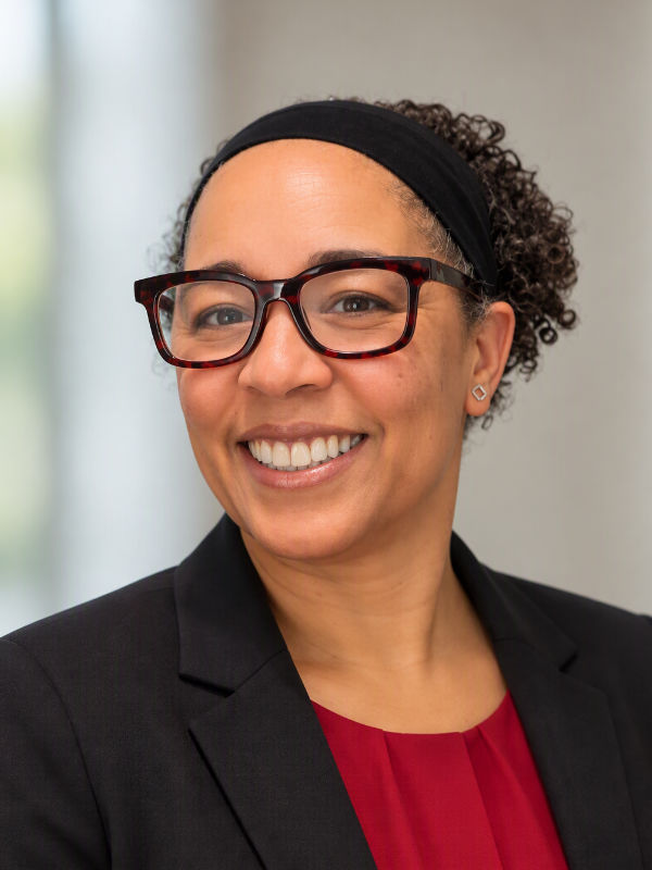 A photo of Eve De Rosa ’91, a person with short dark hair, glasses, and a dark jacket.