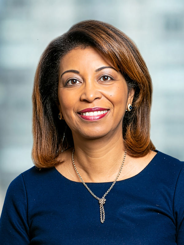 A photo of Mélida Hodgson ’85, a person with long brown hair and a blue shirt.