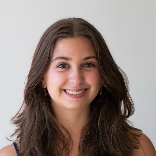A portrait of Jaidyn Stultz, a person with brown hair, wearing a navy patterned camisole and a pendant necklace.