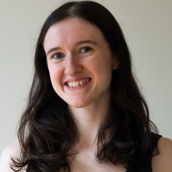 A portrait of Jillian Galimi, a person with dark brown wavy hair, wearing a navy sleeveless top.