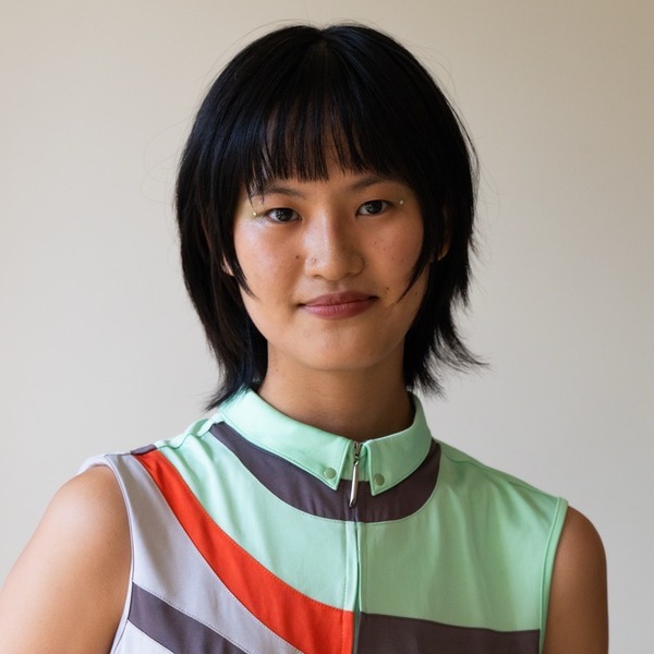 A portrait of Lilianne Liu, a person with black hair, wearing a sleeveless geometric-patterned collared top.