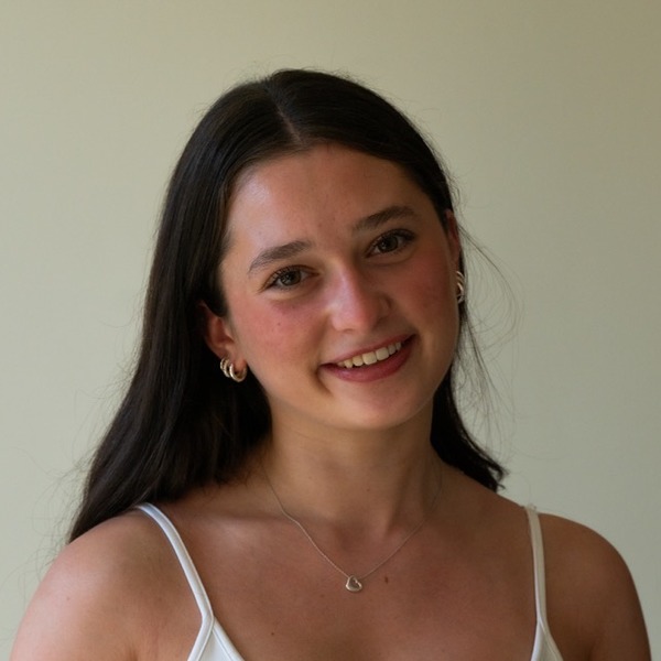 A portrait of Luba Ferencevych, a person with dark brown hair, wearing a white camisole and a pendant necklace.
