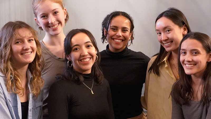 Six people stand in a room, smiling at the camera.