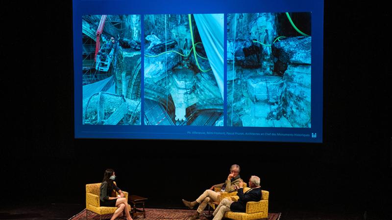 Three people sitting with a projected image in the background.